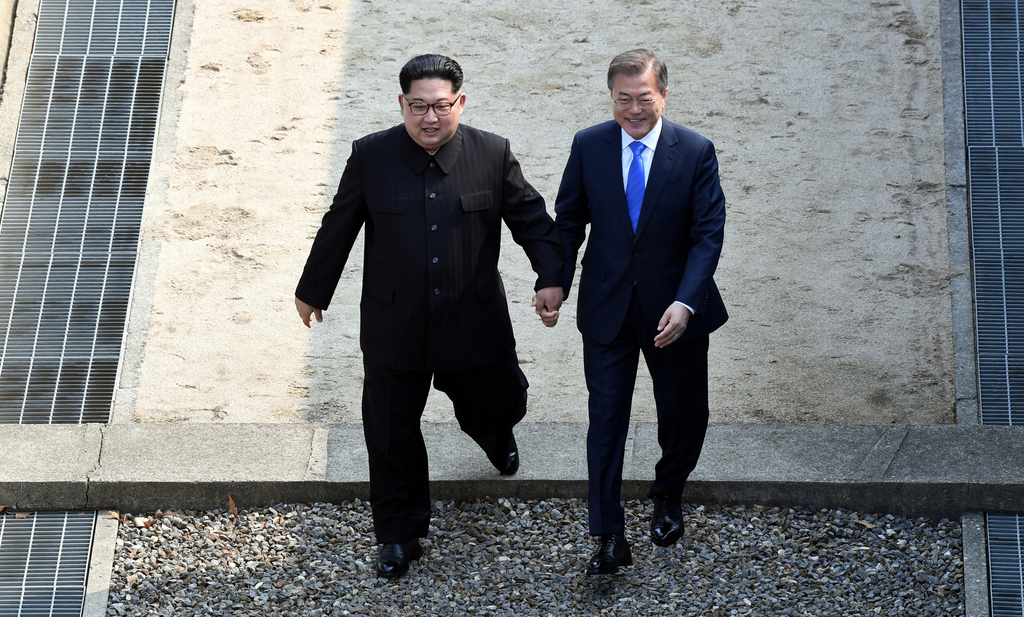 Le dirigeant nord-coréen Kim Jong-un et le président sud-coréen Moon Jae-in au moment de franchir la frontière entre les deux Corées.