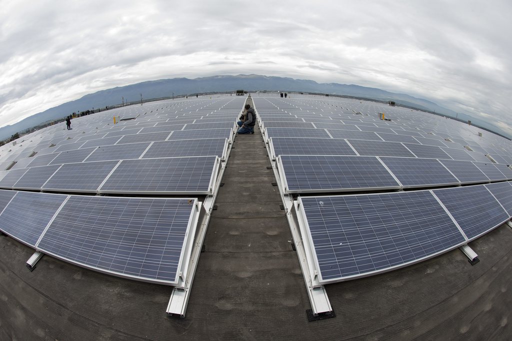 A photographer takes  pictures of solar panels on the roof of the Palexpo Exhibition Center, in Geneva, Switzerland, Tuesday, October 16, 2012. The Palexpo with 15'000 photovoltaic panels for 45'000 m2, is the biggest solar farm in Switzerland. (KEYSTONE/Salvatore Di Nolfi)