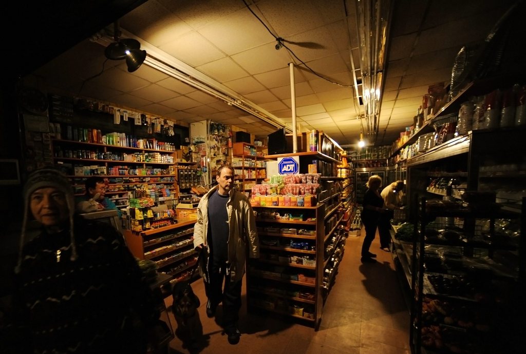 epa03454166 People shop in a grocery store with lights from a portable generator on Bleeker Street in New York City, New York, USA, 31 October 2012. Hurricane Sandy has knocked out power to much of lower Manhattan and has forced many residents to seek shelter in other parts of the city. The storm, one of the largest to hit the region in decades has caused massive destruction of the city's infrastructure.  EPA/PETER FOLEY