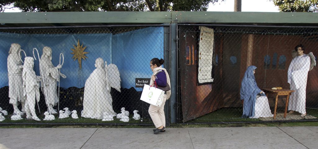 FILE - In this Dec. 13, 2011 file photo, a woman walks past a two of the traditional displays showing the Nativity scene along Ocean Avenue at Palisades Park in Santa Monica, Calif. Avowed atheist Damon Vix last year won two-thirds of the booths in the annual, city-sponsored lottery to divvy up spaces in the live-sized Nativity display.  But he only put up one thing: A sign that read "Religions are all alike - founded on fables and mythologies." Vix left the rest of his allotted spaces empty, and in so doing, upended a Christmas tradition that began in Santa Monica nearly 60 years ago. (AP Photo/Ringo H.W. Chiu, file)