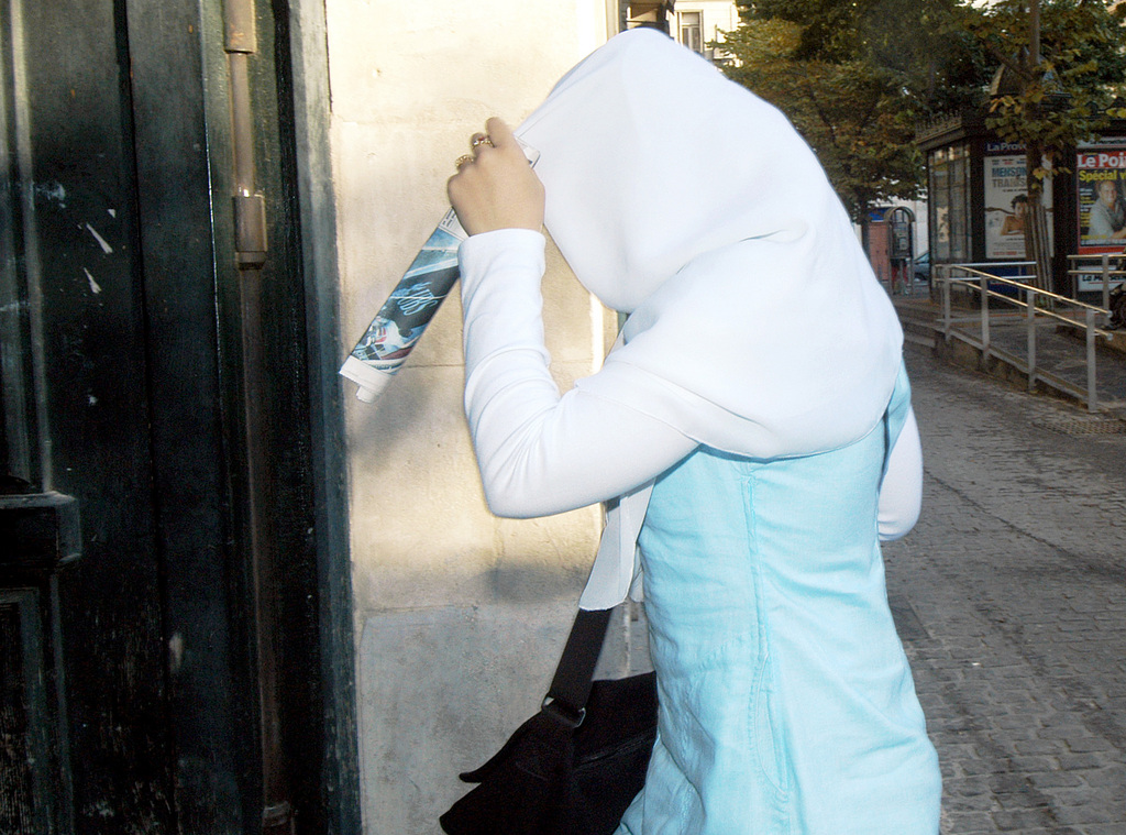 A veiled schoolgirl hides her face from a photographer before entering the Montgrand high school in Marseille, southern France, Friday,  Sept. 3, 2004 on their first school day. France's new law banning Islamic head scarves in schools apparently  passed its first test Thursday, the start of the school year. There were no major incidents and only a few known cases of girls refusing to comply. This girl took off her veil inside the school.(AP Photo/Claude Paris)