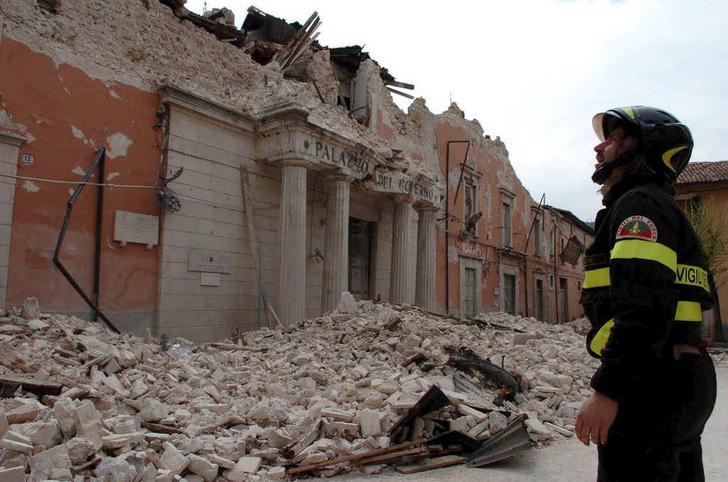 epa01695413 An Italian fireman looks on a collapsed offcial building 'Palazzo del Governo' in L'Aquila, Abruzzo Region, Italy on 12 April 2009. Thousands of people made homeless by Italy's deadliest earthquake in 30 years celebrated a sombre Easter on Sunday, huddling for mass at makeshift chapels set up in tent cities and emergency shelters. Six days after disaster struck the central city of L'Aquila and 26 surrounding towns, killing 294 people, survivors prayed for the dead and sought comfort in religion to help them rebuild shattered lives.  EPA/SCHIAZZA