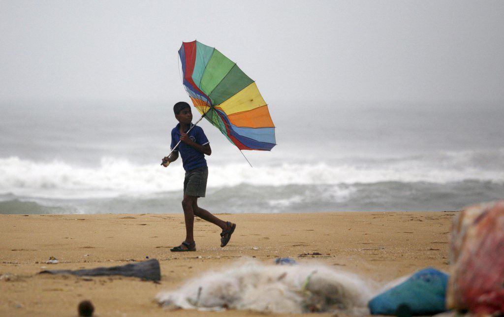 Une jeune Indien retient son parapluie contre les vents puissants du cyclone Nilam dans la région de Chenai. 