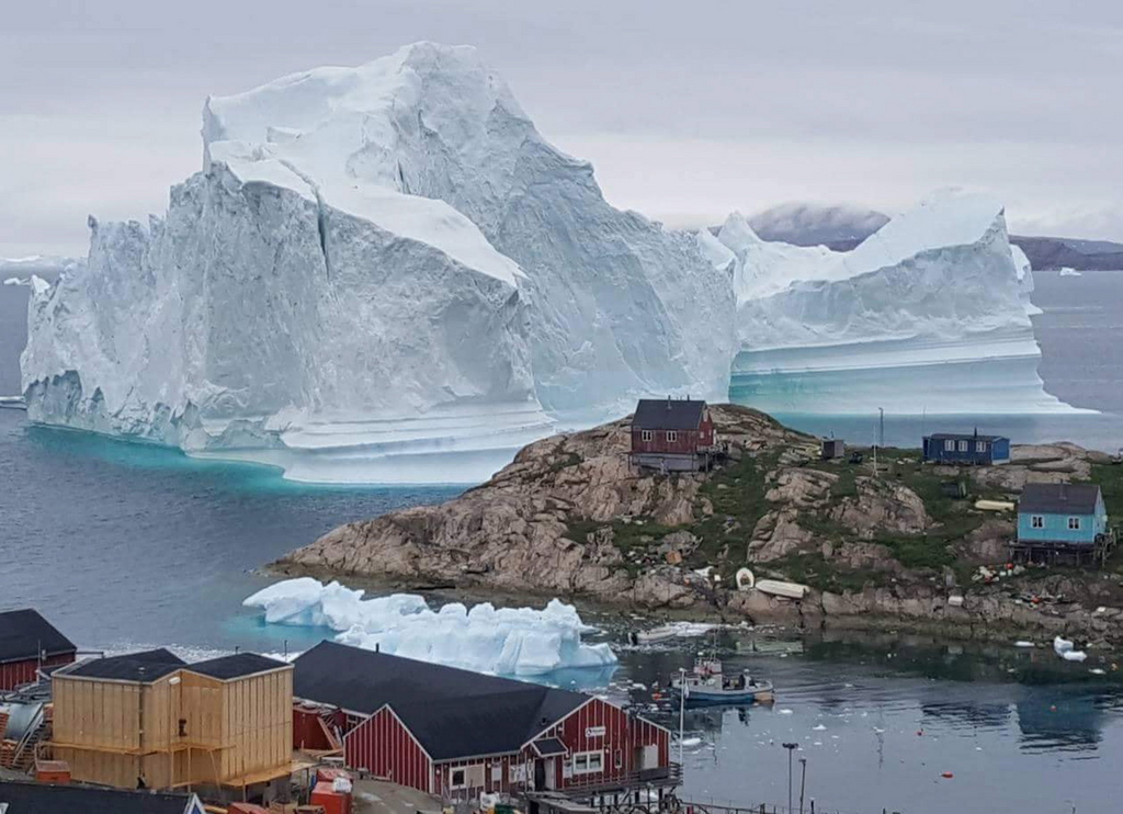 L'iceberg dépasse les toits de maisons construites sur un promontoire du village d'Innaarsuit.