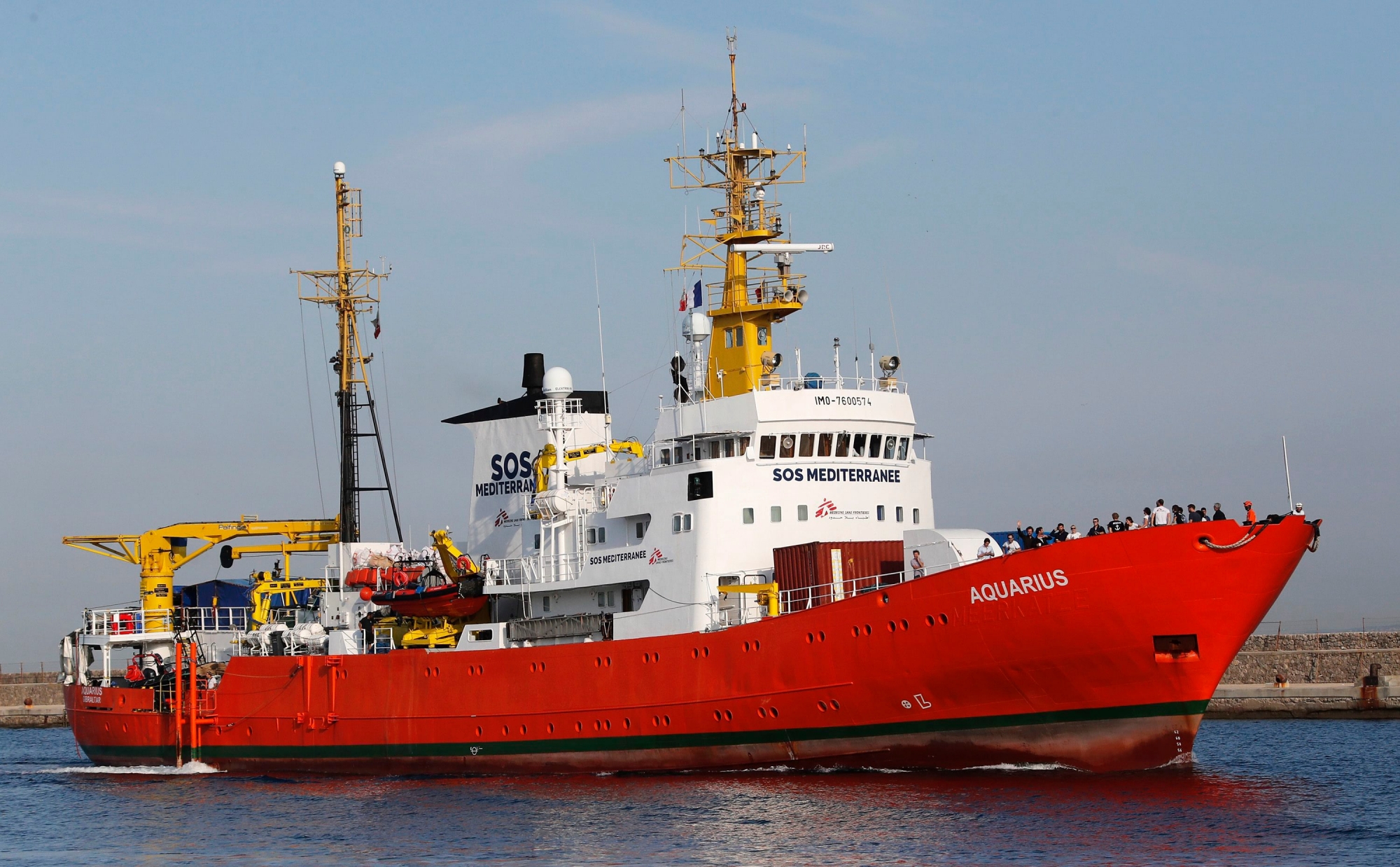 epa06849219 Crew members of the search and rescue vessel 'Aquarius' of NGO 'SOS Mediterranee' wave from the ship's bow as the vessel arrives in the port of Marseille, France, 29 June 2018. The 'Aquarius' arrives in the port for a five-days stop and check up after rescue operations in the Mediterranean Sea.  EPA/GUILLAUME HORCAJUELO FRANCE MIGRATION RESCUE