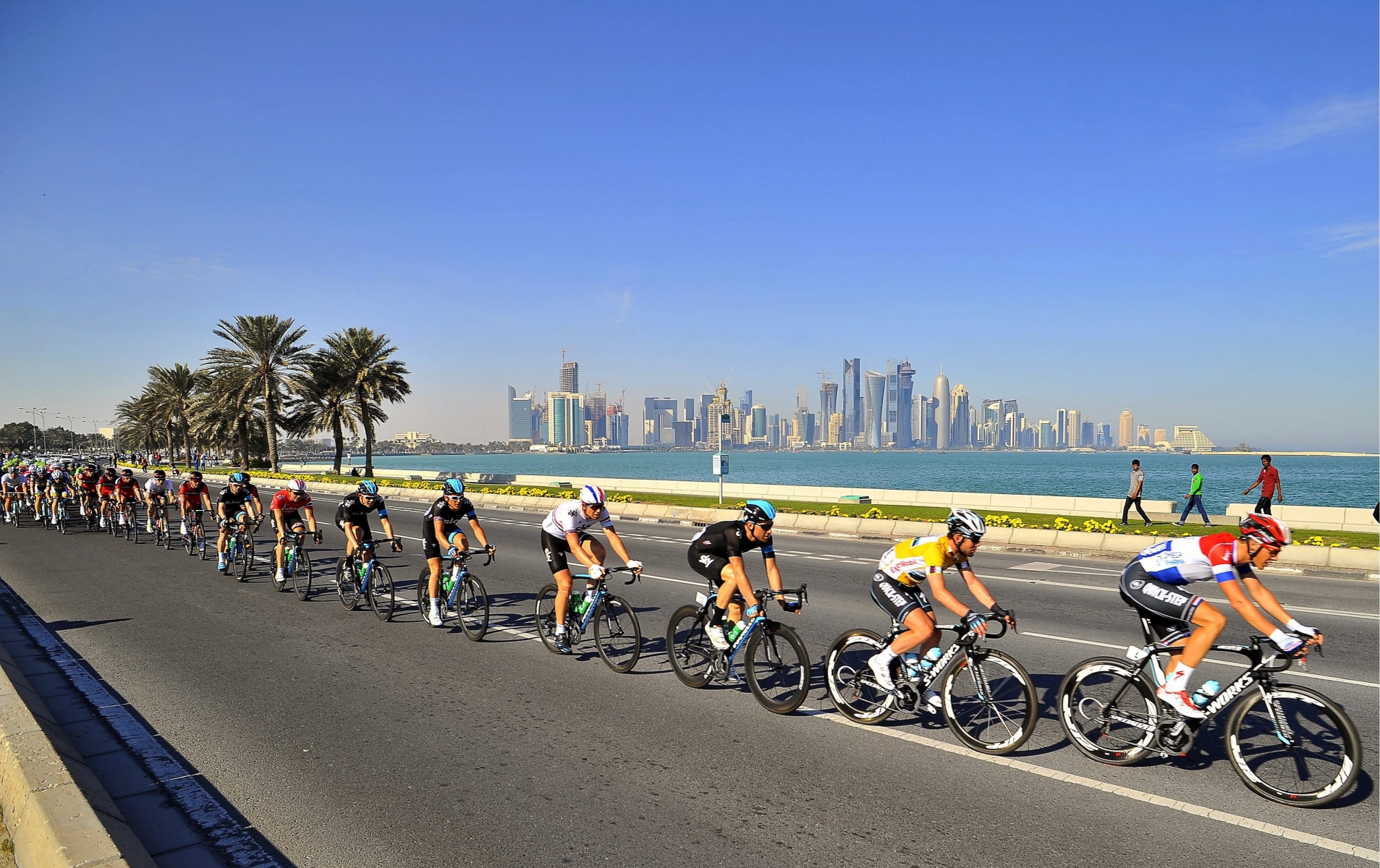 epa03573690 British rider Mark Cavendish (2nd R) of the Omega Pharma Quick Step team rides in the pack on his way to win the sixth stage and the Tour of Qatar cycling race between Sealine Beach Resort and Doha Corniche, Qatar, 08 February 2013. In background the skyline of Doha.  EPA/NICOLAS BOUVY