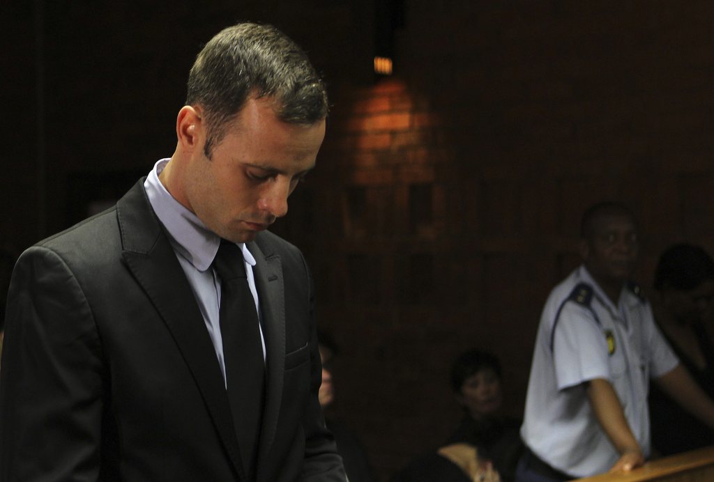 Olympic athlete Oscar Pistorius stands inside the court as a police officer looks on during his bail hearing at the magistrate court in Pretoria, South Africa, Wednesday, Feb. 20, 2013. A South African judge says defense lawyers will need to offer "exceptional" reasons to convince him to grant bail for Oscar Pistorius, when a hearing resumes Wednesday. (AP Photo/Themba Hadebe)
