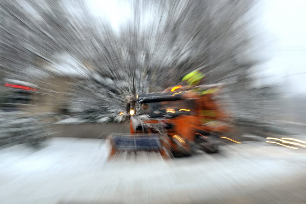 Un chasse-neige enleve de la neige fraiche tombee durant la nuit dans la region de Geneve, ce mercredi 13 janvier 2010. Il est tombe 10 a 15 centimetres de neige durant la nuit de mardi a mercredi. (KEYSTONE/Martial Trezzini)