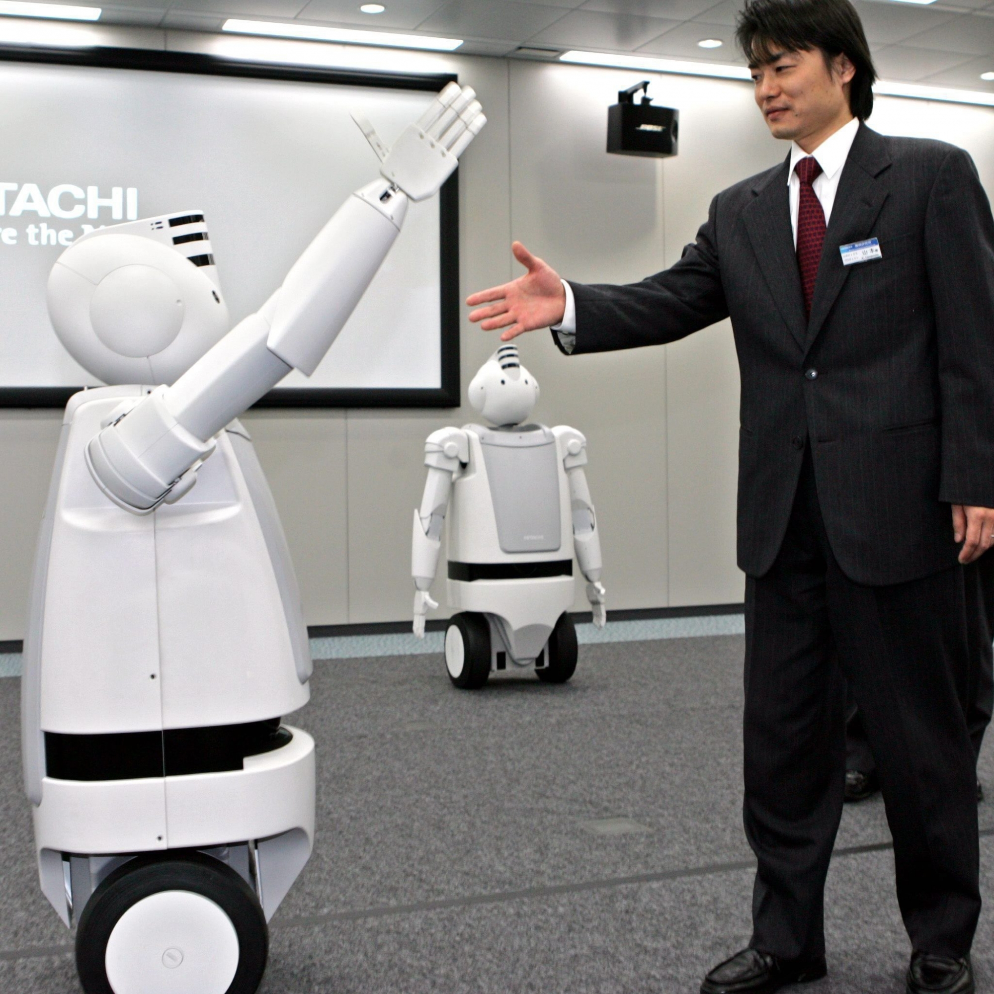 EMIEW, a child-size robot-on-wheels from Japanese electronics maker Hitachi Ltd. , reacts to Kenjiro Yamamoto, Hitachi's engineer, during a demonstration in Tokyo Tuesday, March 15, 2005. EMIEW, which stands for "excellent mobility and interactive existence as workmate," avoids obstacles in its way, responds to simple voice commands and reads the weather forecast. The robot was developed for display at the World Exposition in Aichi, central Japan, which opens this month.  (KEYSTONE/AP/Katsumi Kasahara) JAPAN ROBOT