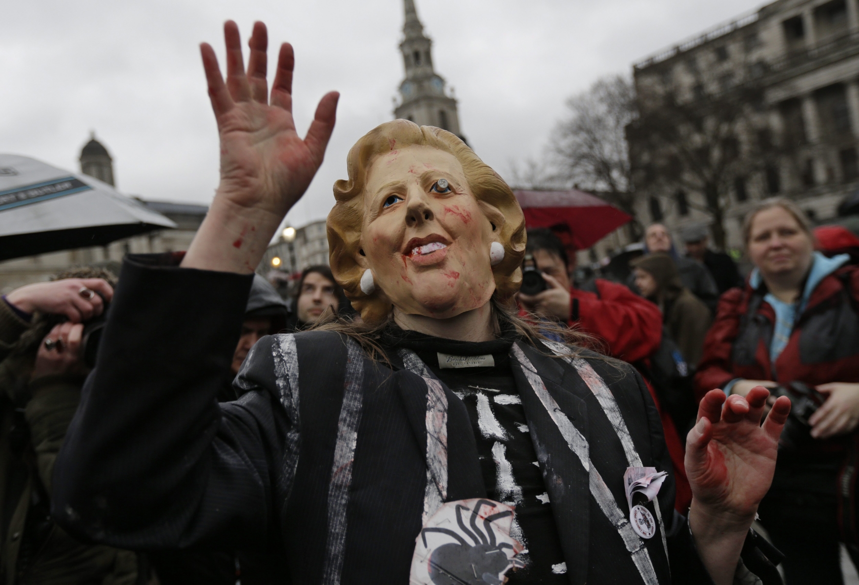 A protester wears a mask depicting former British Prime Minister Margaret Thatcher during a party to mark her death in central London's Trafalgar square, Saturday, April 13, 2013. Thatcher's most strident critics had long vowed to hold a gathering in central London on the Saturday following her passing, and the festivities were an indication of the depth of the hatred which some Britons still feel for their former leader. (AP Photo/Lefteris Pitarakis)