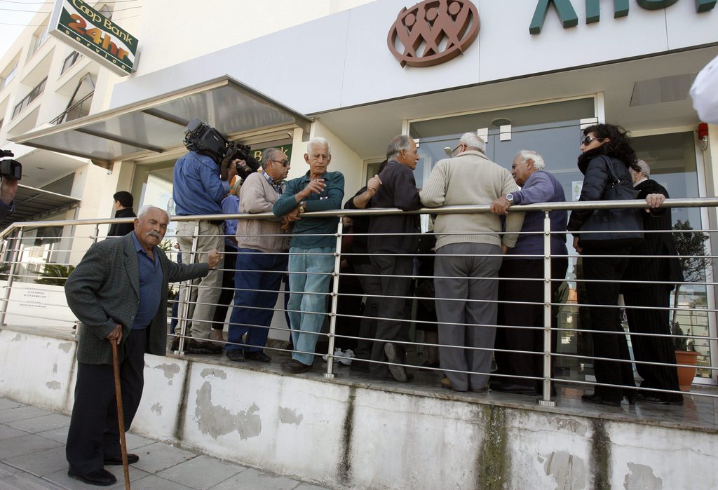 People wait outside a Coop Bank branch in Nicosia, Cyprus, Thursday, March 28, 2013. Cypriots get their first chance to access their savings in almost two weeks when the country?s banks reopen Thursday - albeit with strict restrictions on transactions - after being closed due to the country?s acute financial crisis. Lines were starting to form outside banks Thursday morning ahead of the official opening for six hours at noon (1000 GMT). (AP Photo/Philippos Christou)