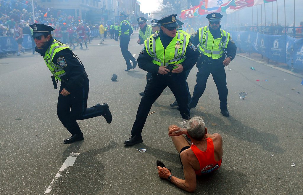 ADDS IDENTIFICATION OF RUNNER- BILL IFFRIG- Bill Iffrig, 78, lies on the ground as police officers react to a second explosion at the finish line of the Boston Marathon in Boston, Monday, April 15, 2013. Iffrig, of Lake Stevens, Wash., was running his third Boston Marathon and near the finish line when he was knocked down by one of two bomb blasts. (AP Photo/The Boston Globe,  John Tlumacki)