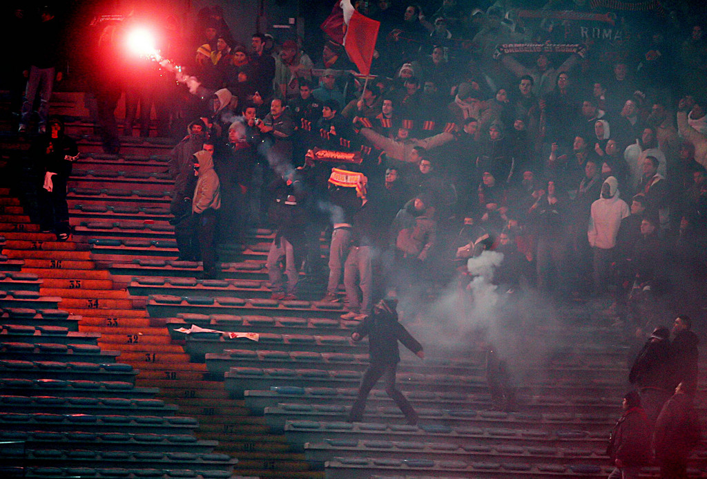 A Roma's supporter throws a flare during the Italian Serie A top league soccer match between Roma and Milan at Rome's Olympic stadium, Sunday, in this Jan. 15, 2006 photo. England was long notorious as the home of the soccer hooligan, but CCTV cameras, tougher policing and higher ticket prices have tamed stadium violence. Now Italy, France and the Netherlands are becoming known as the European countries where the worst soccer violence takes place. Thanks to Italy's World Cup final victory over France last July in Germany, Italian soccer managed to recover from a match-fixing scandal that had greatly undermined its credibility. But last Friday's violence promises to be a harder crisis to overcome. (AP Photo/Gregorio Borgia)