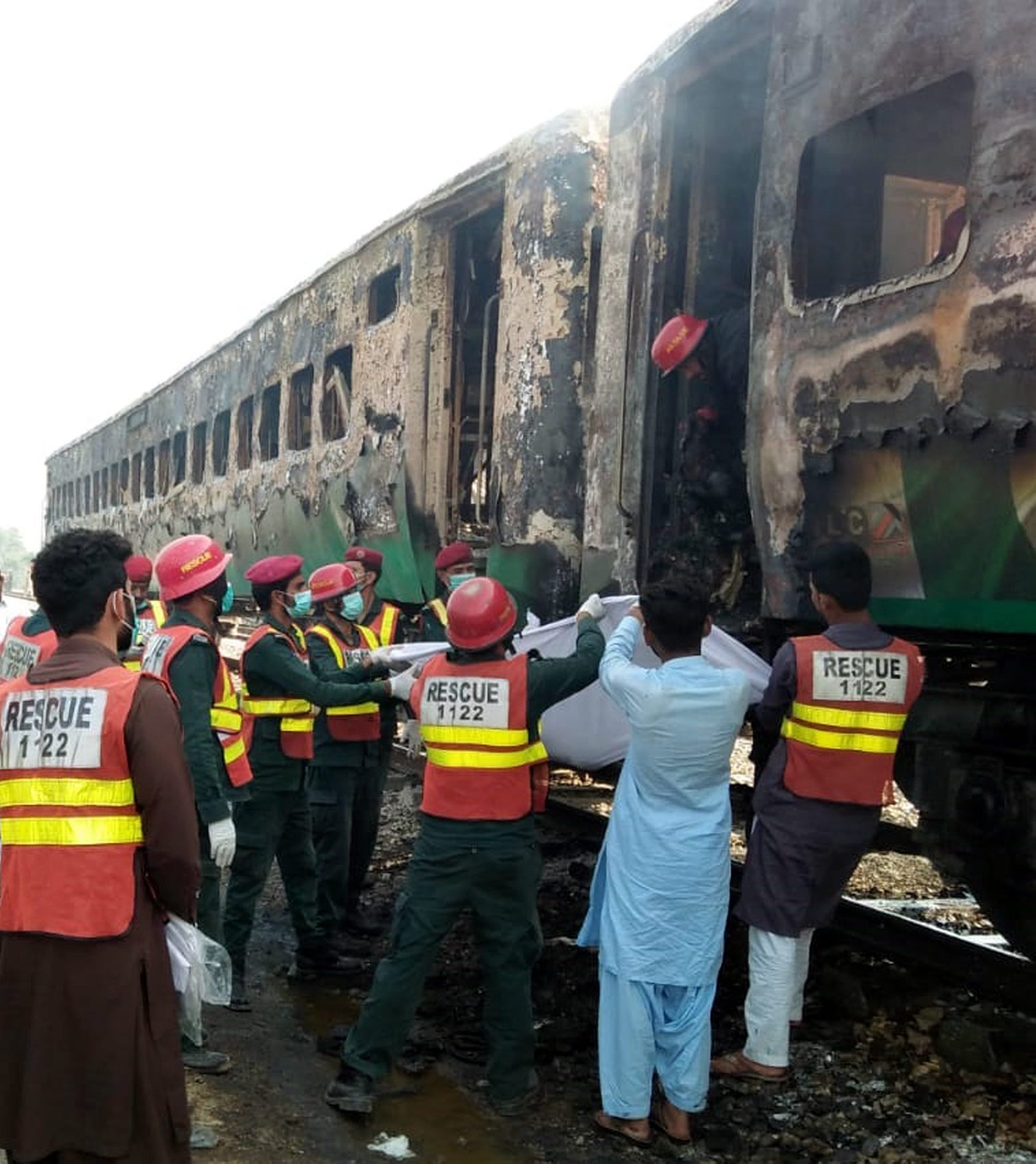 epa07961657 Rescue workers shift the bodies of the victims after a fire engulfed a passenger train near Rahim Yar Khan, Pakistan, 31 October 2019. Dozens were killed and more than 40 others injured after a fire erupted from a gas canister blast engulfed a train completely destroying at least three coaches.  EPA/STRINGER ATTENTION: GRAPHIC CONTENT PAKISTAN FIRE TRANSPORT ACCIDENT