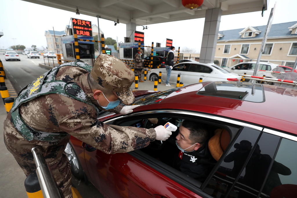 Un soldat prend la température d'un automobiliste à un poste de péage autoroutier à Wuhan. Toutes les personnes sont contrôlées afin de contenir le virus.