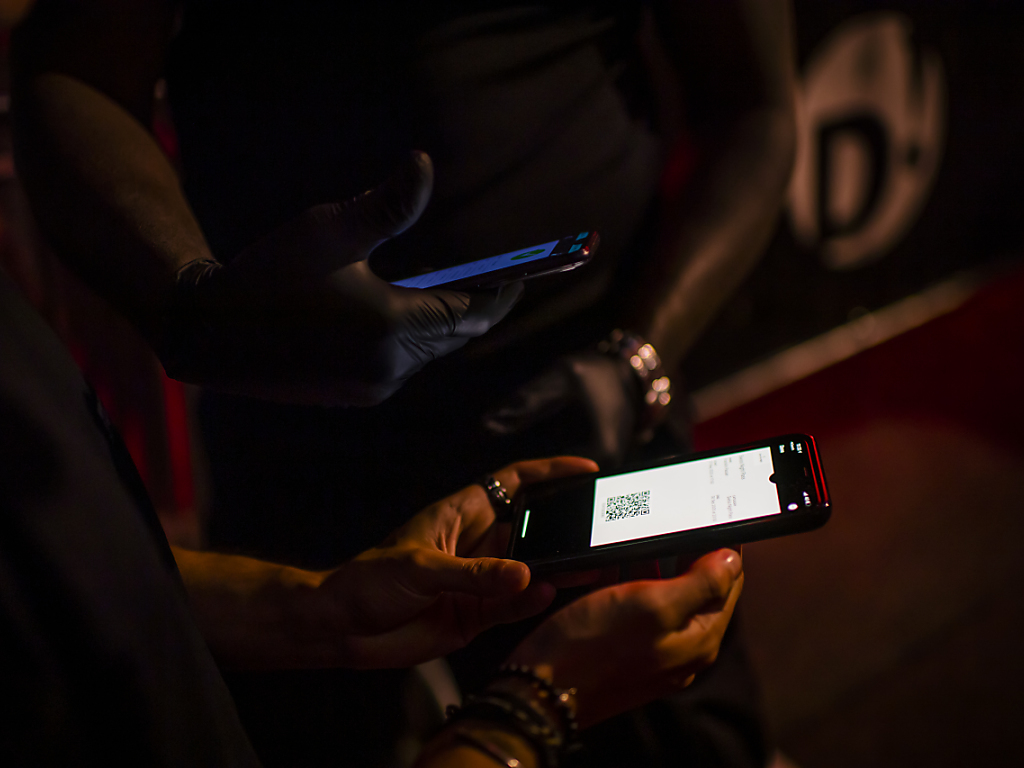 Un agent de sécurité scanne le QR Code de l'application Swiss Pass Night d'un client devant une discothèque à Lausanne.